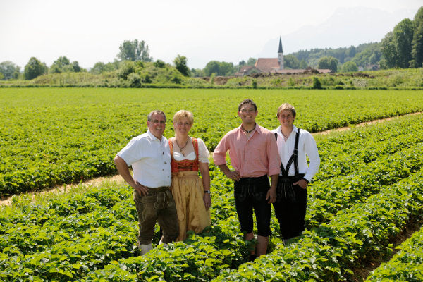 Familie auf Erdbeerfeld stehend.