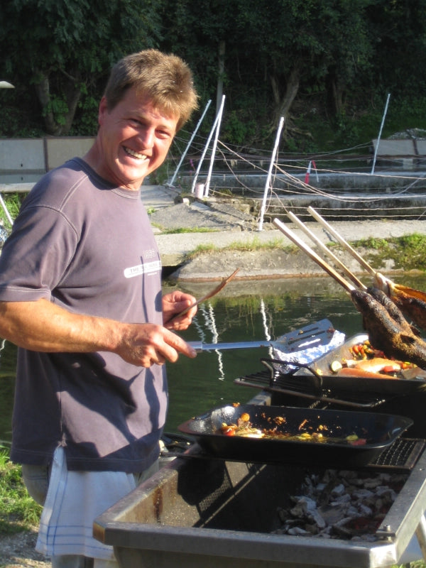 Mann grillt Fisch im Freien