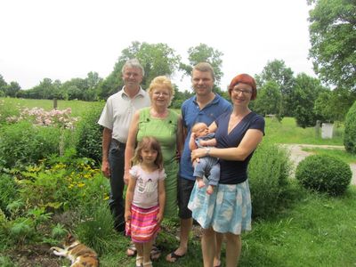Familie im Garten vor Hofladen.
