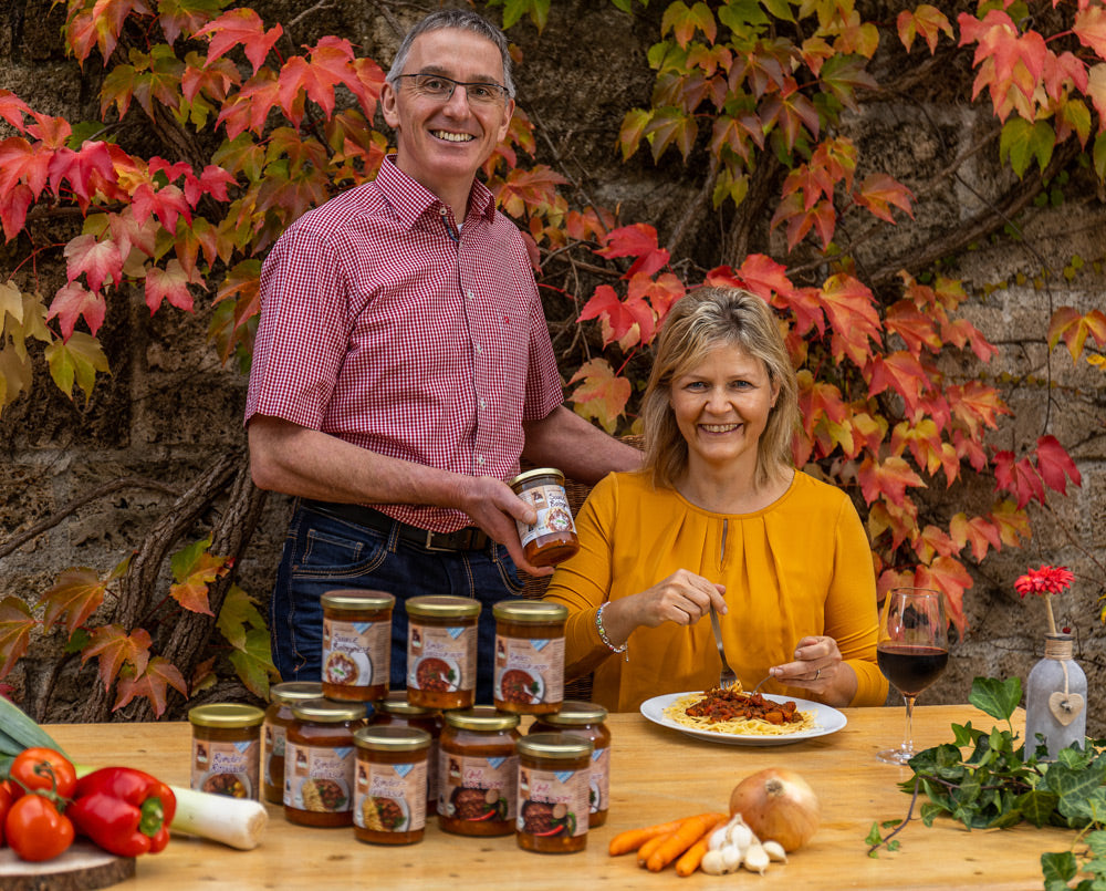 Personen mit Hofladenprodukten vor Laubwand.